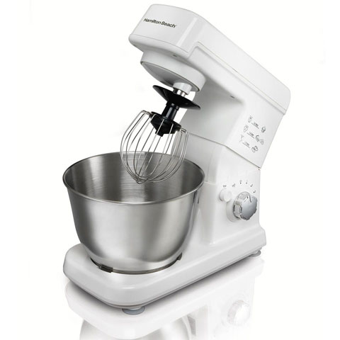 Front angle view of this mixer, with head tilted up, whisk attachment installed, and the mixing bowl placed on the base